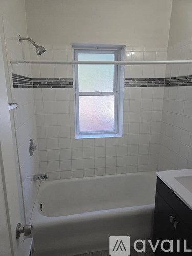 A white bathroom with a tub and a window.