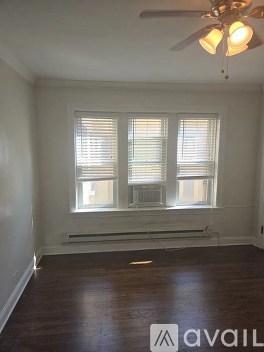 A room with a ceiling fan and a window with blinds.