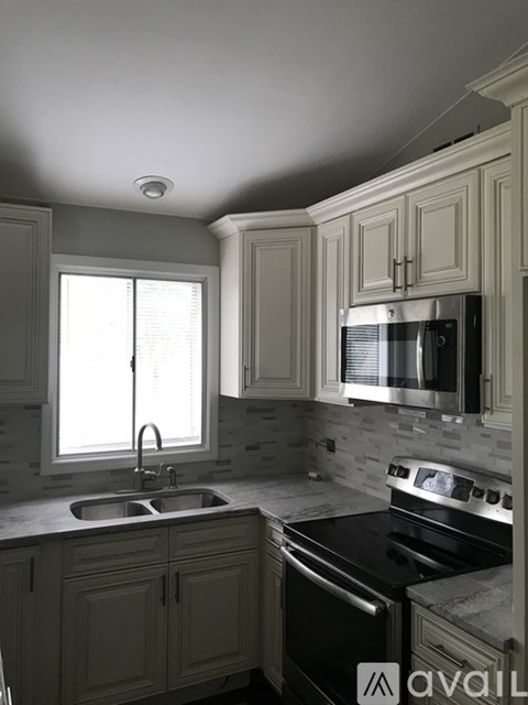 A kitchen with a sink, stove, and cabinets.