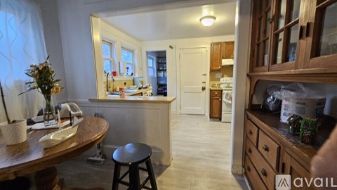 A kitchen with wooden cabinets and a round table with a vase on it.