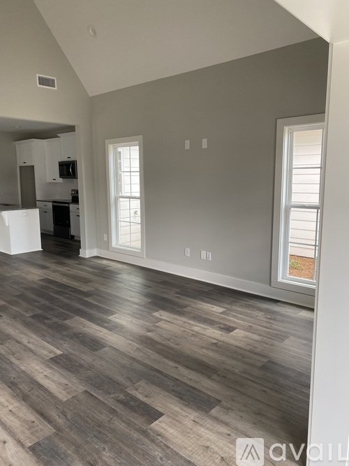 A room with wooden flooring and a window on the right side.