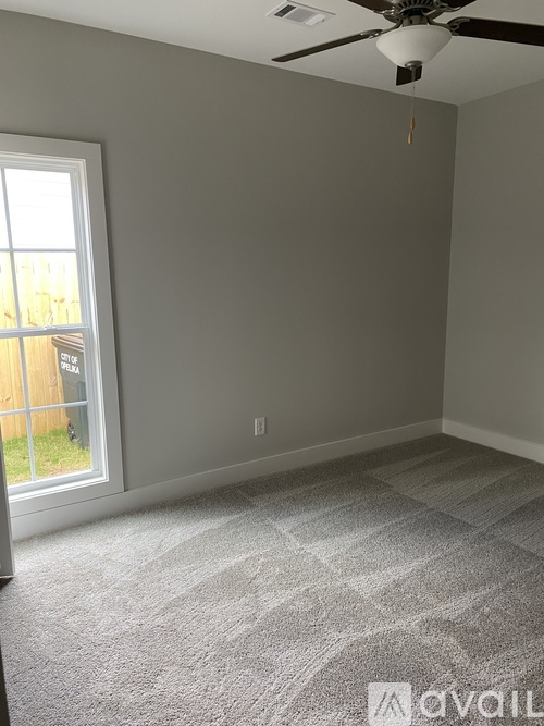 A room with a carpeted floor and a ceiling fan.