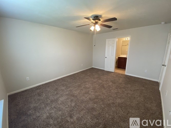 A room with a carpeted floor and a ceiling fan.