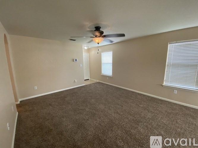 A room with a carpeted floor and a ceiling fan.