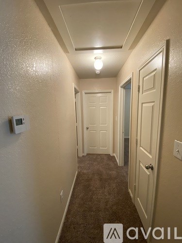 A hallway with a carpeted floor and white walls.