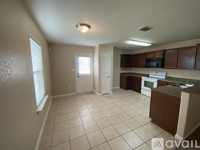 A kitchen with white tiled floors and brown cabinets.
