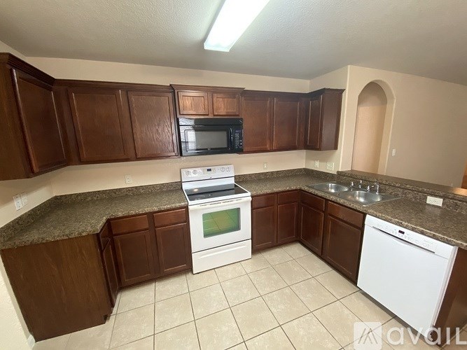 A kitchen with brown cabinets and white appliances.