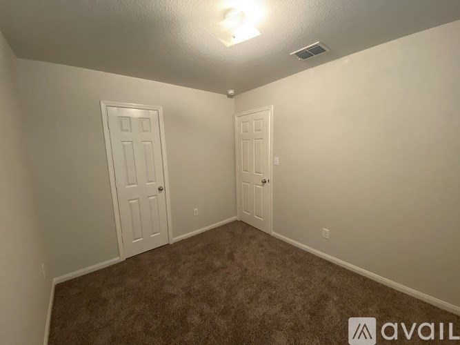 A room with two doors and carpeted floor.