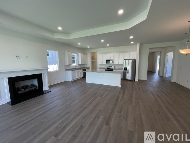 A spacious living room with wood flooring and a fireplace.