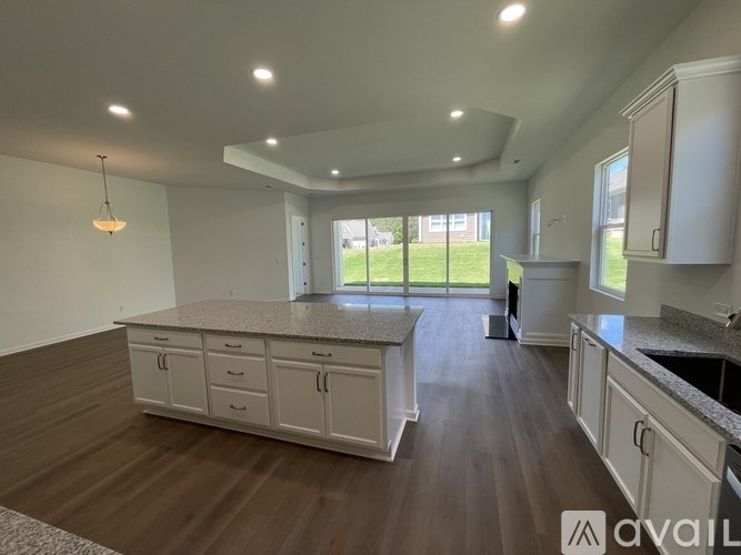 A spacious kitchen and living room with white cabinetry and wood flooring.