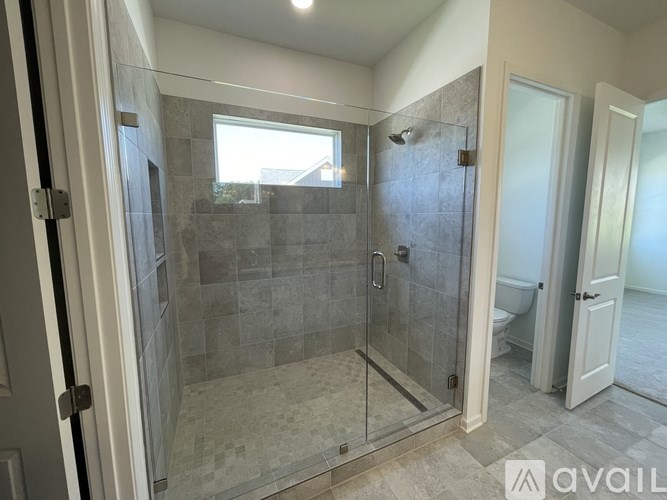 A bathroom with a walk-in shower and a toilet in the background.