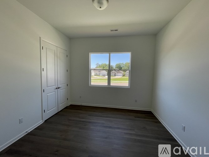 A room with a window showing a view of a house across the street.