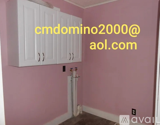 A room with pink walls and white cabinets.