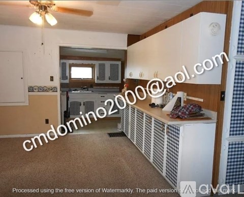 A kitchen with white cabinets and a checkered wallpapered wall.