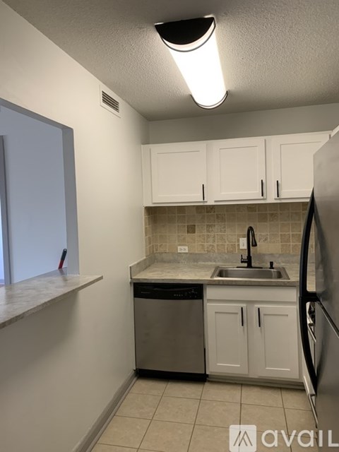 A kitchen with white cabinets and a black refrigerator.