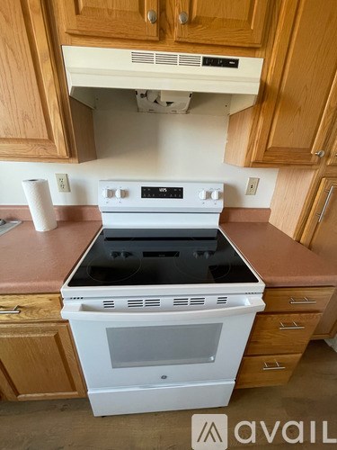 A white oven with a black bottom is in a kitchen with wooden cabinets.