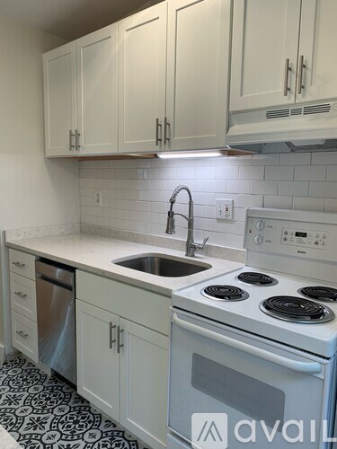 A kitchen with white cabinets and a black and white floor.