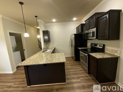 A kitchen with dark brown cabinets and a granite countertop.