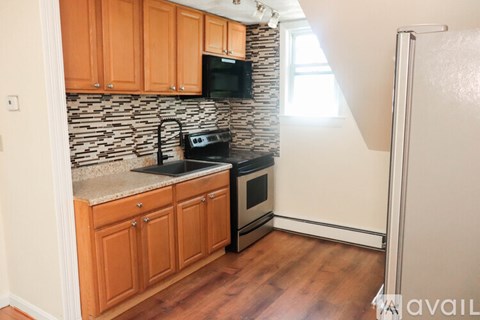 A kitchen with wooden cabinets and a black microwave above the stove.