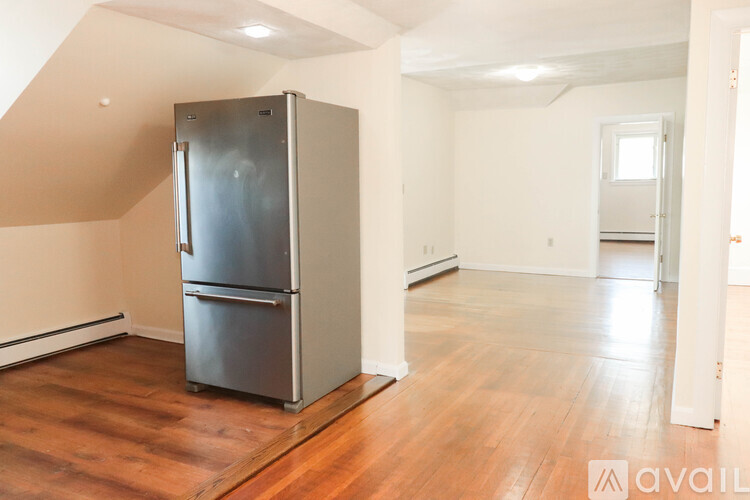 A stainless steel refrigerator in a room with wooden floors and white walls.