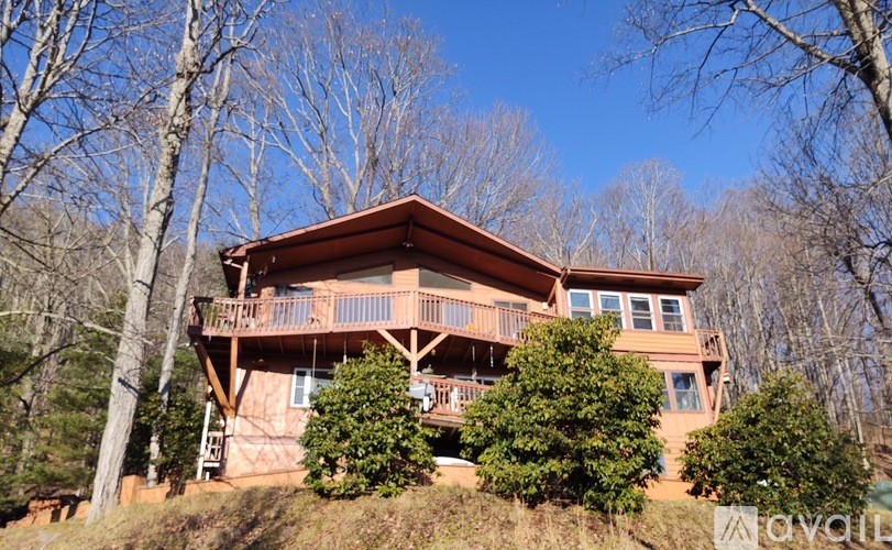 A large wooden house with a balcony surrounded by trees.