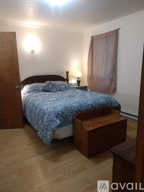 A bedroom with a bed, nightstand, and chair.