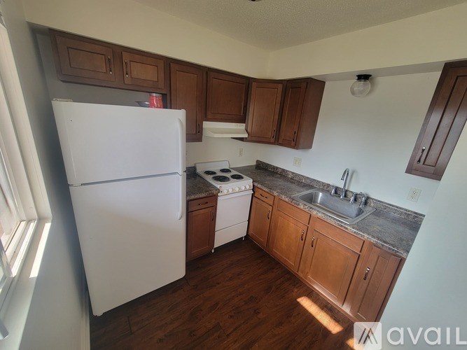 A kitchen with a white refrigerator, a white stove, and brown cabinets.