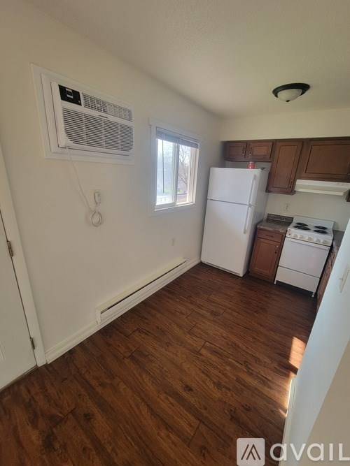 A kitchen with white appliances and wooden floors.
