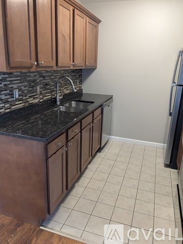 A kitchen with brown cabinets and a black counter top.