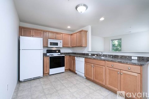 A kitchen with white appliances and wooden cabinets.