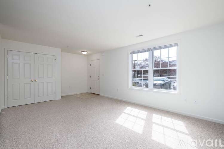 A spacious room with a large window and a carpeted floor.