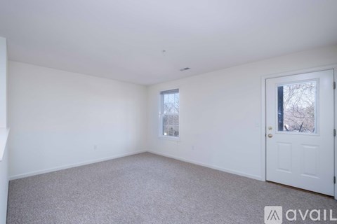 A spacious room with a large window and a carpeted floor.