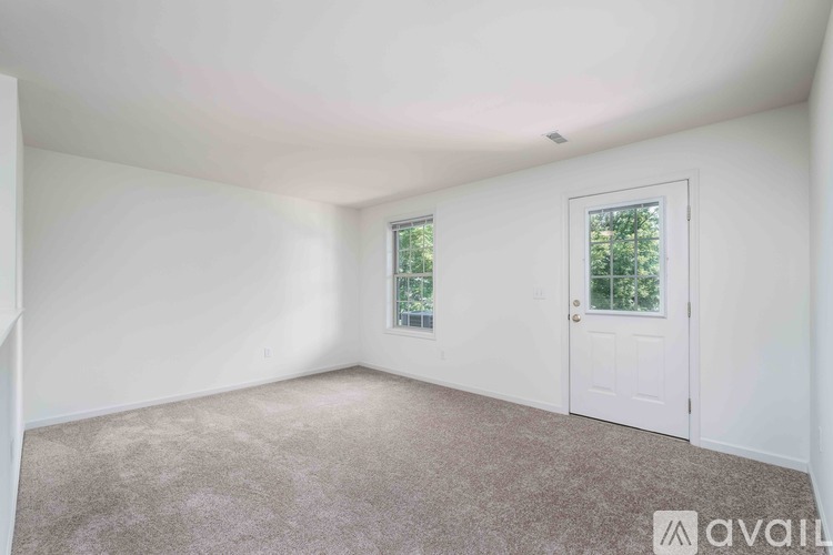 A room with a window and a carpeted floor.
