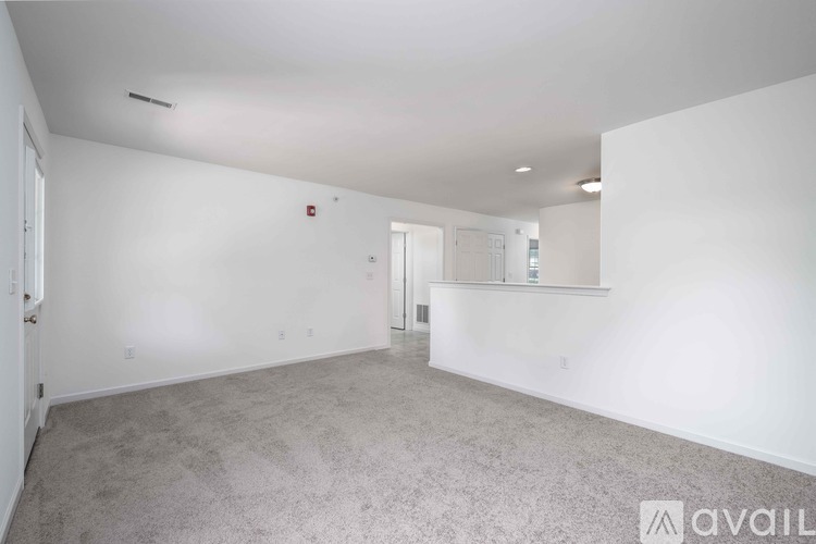 A spacious empty room with a carpeted floor and white walls.