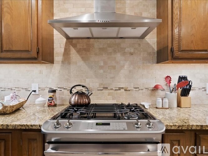 A modern kitchen with a stove top oven and wooden cabinets.