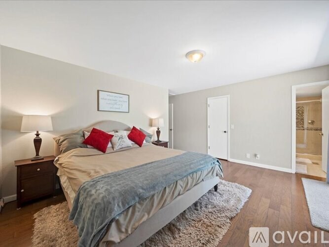 A bedroom with a bed, nightstand, and a rug.