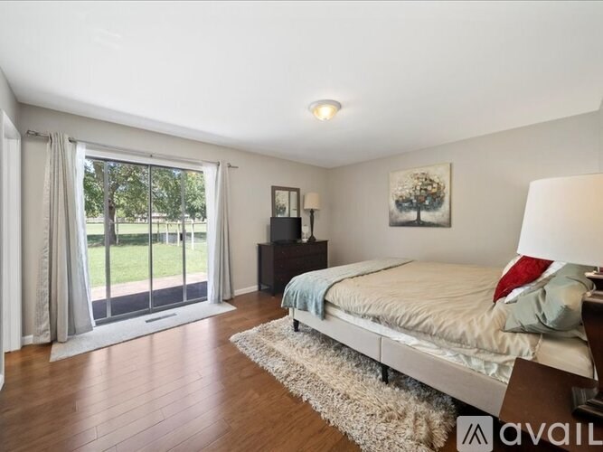 A bedroom with a large bed and a sliding glass door leading to a garden.