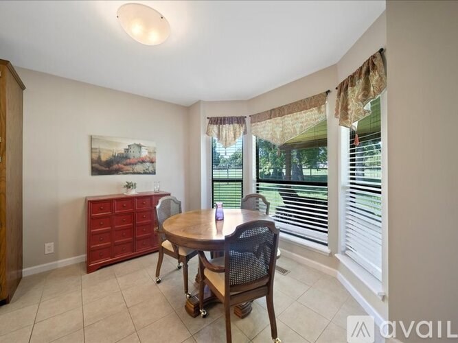 A dining room with a table, chairs, and a painting on the wall.