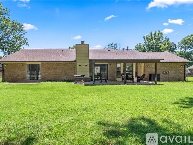 A house with a brown roof and a large lawn in front.