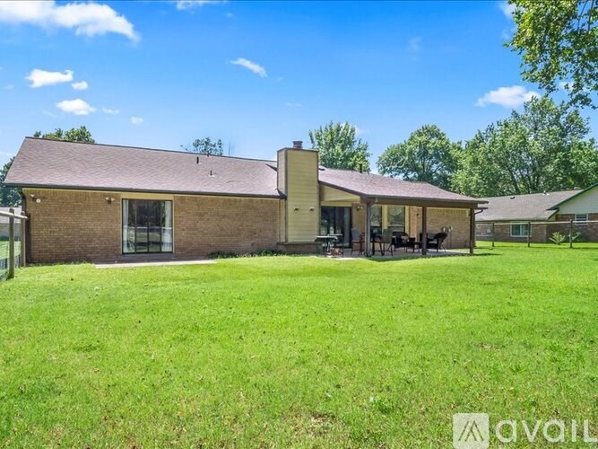 A house with a brown roof and a green lawn in front.