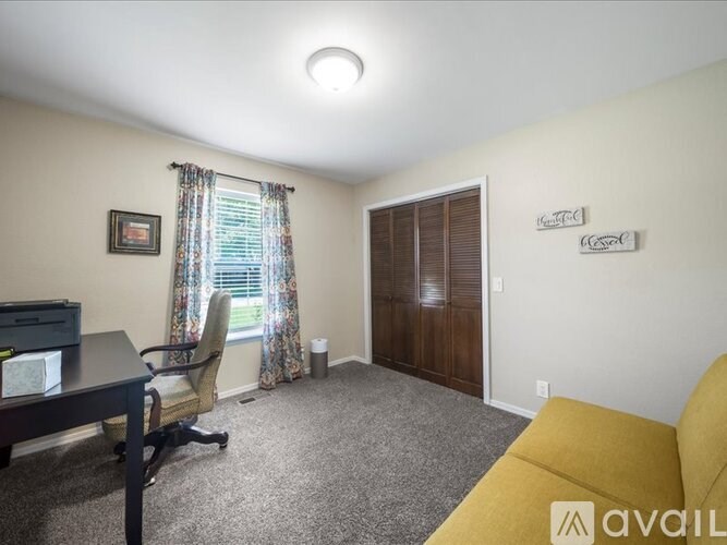 A room with a desk, chair, and a window with curtains.