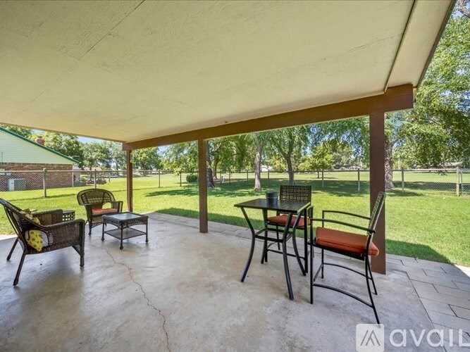 A patio with a table and chairs under a roof.