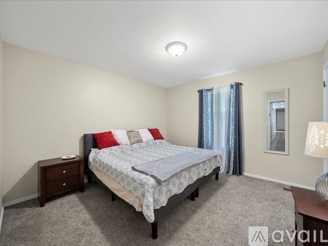 A bedroom with a bed, nightstand, and window.