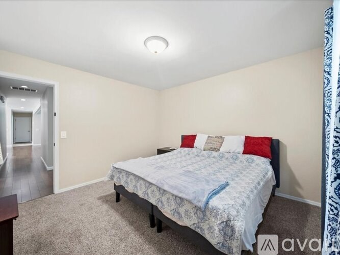 A bedroom with a bed, pillows, and a carpeted floor.