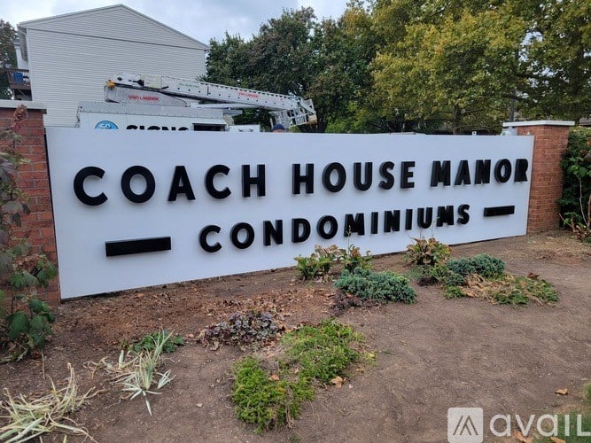 A sign for Coach House Manor Condominiums is displayed in front of a building.