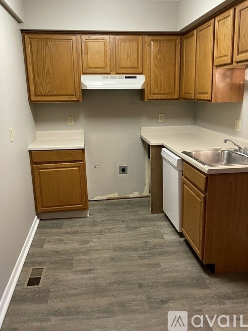 A kitchen with wooden cabinets and a white dishwasher.