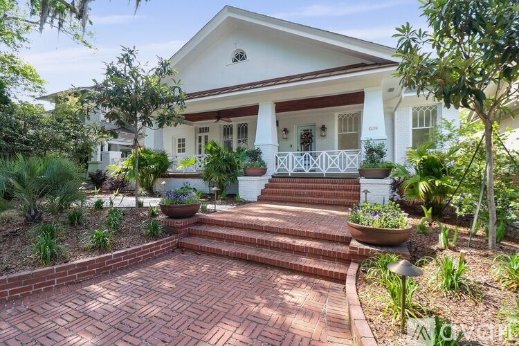 A white house with a red brick walkway leading to the front door.