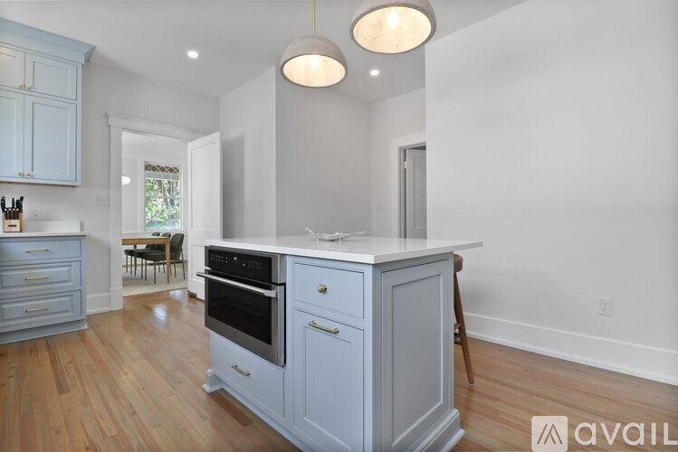 A kitchen with a grey island and a wooden floor.
