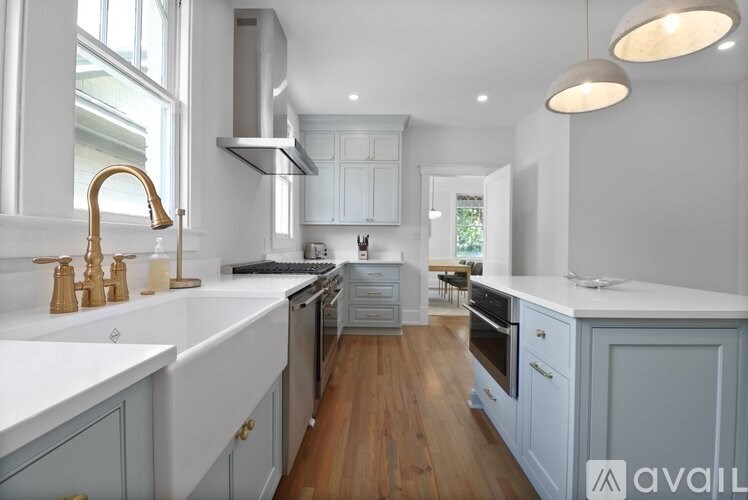 A kitchen with white and grey cabinets and a wooden floor.