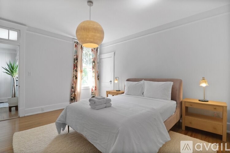 A bedroom with a large bed and a wooden nightstand.